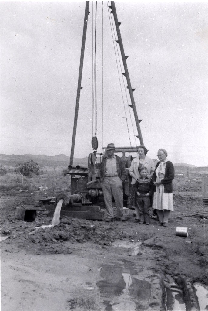 People in front of a water well being drilled